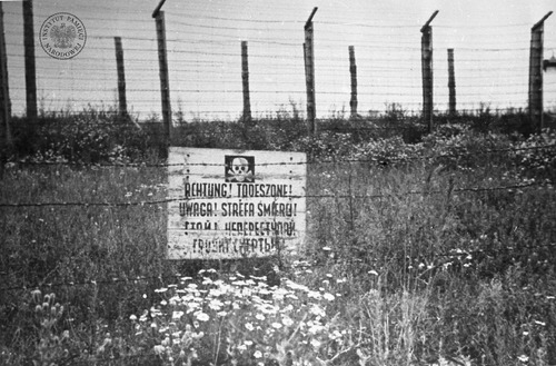 Ogrodzenie obozu na Majdanku – dwa rzędy betonowych słupów z drutem kolczastym. Widoczna tablica z napisem w językach niemieckim, polskim i rosyjskim: „Uwaga! Strefa śmierci!”. Fot. Stanisław Magierski. Zdjęcie wykonane po wyzwoleniu KL Lublin w lipcu 1944 r. Fot. z zasobu IPN