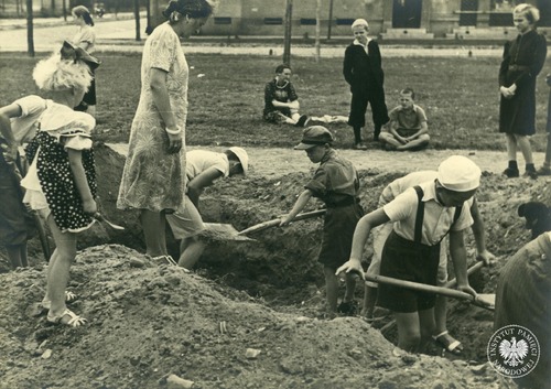 Grupa dzieci kopie rów przeciwlotniczy na skwerze przy alei Wojska Polskiego na warszawskim Żoliborzu – wrzesień 1939 r. (fot. z zasobu AIPN)