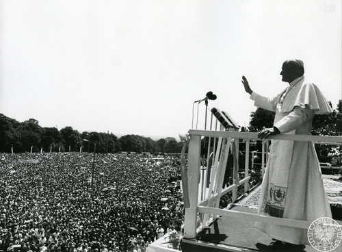Jan Paweł II w otoczeniu duchownych pozdrawia wiernych zgromadzonych na błoniach jasnogórskich z podium ołtarza papieskiego na wałach klasztoru na Jasnej Górze (fot. z zasobu IPN)