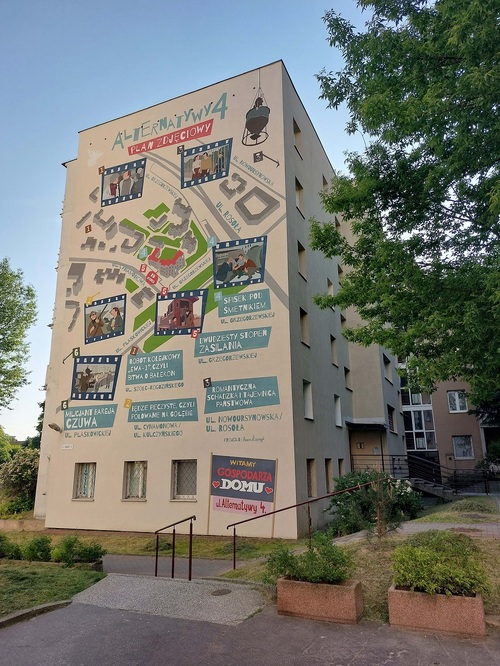 Mural na ścianie bloku, w którym realizowany był serial „Alternatywy 4”. Przedstawia lokalizację miejsc na Ursynowie, w których kręcono poszczególne sceny. Uwieczniony został także reżyser serialu. Projekt elewacji został sfinansowany przez Dzielnicę Ursynów m.st. Warszawy w ramach budżetu partycypacyjnego. Autorem projektu murala jest Marcin Ślusarczyk (fot. P. Zielony, 2023 r.)