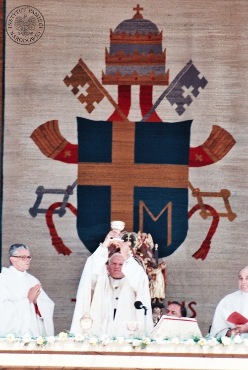 Jan Paweł II unosi kielich z konsekrowanym winem w czasie mszy beatyfikacyjnej brata Alberta Chmielowskiego i ojca Rafała Kalinowskiego. Obok papieża metropolita krakowski kardynał Franciszek Macharski (pierwszy od lewej), za papieżem klęczy mistrz papieskich ceremonii liturgicznych ksiądz John Magee. Kraków, 22 czerwca1983 roku