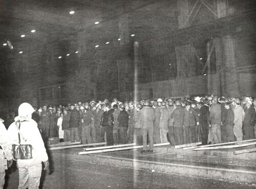 Funkcjonariusze MO (z przodu, z lewej) pilnujący dużej grupy strajkujących robotników, na terenie Walcowni Kombinatu Metalurgicznego Huty im. Lenina w Krakowie.