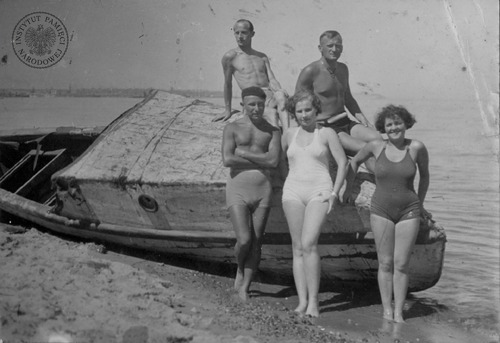 Plażowicze w strojach kąpielowych pozują do zdjęcia przy łódce nad brzegiem Morza Bałtyckiego, okres przedwojenny (fot. z zasobu IPN)