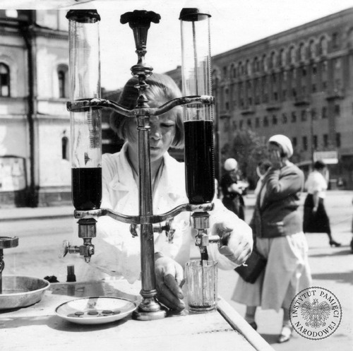 Młoda kobieta nalewa z saturatora sok do szklanki na placu Puszkina. Moskwa, 1935 r. Zdjęcie z kolekcji Juliena Bryana (fot. z zasobu AIPN)
