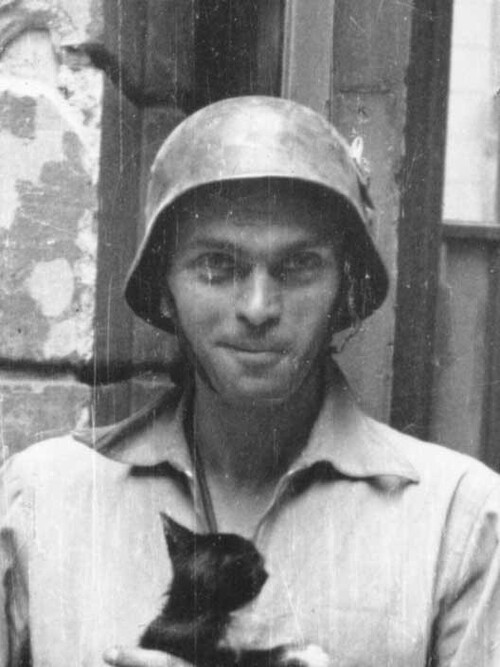 Ppor. Eugeniusz Lokajski "Brok" stojący z kotkiem na podwórzu gmachu dawnego Towarzystwa Ubezpieczeń "Rosja" przy ulicy Marszałkowskiej 124/128 (fragment), domena publiczna