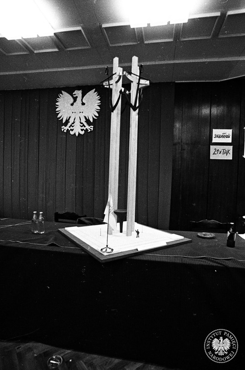 Makieta pomnika Poległych Stoczniowców w sali BHP w czasie strajku w Stoczni Gdańskiej. Pomnik, odsłonięty w grudniu 1980 r., powstał w dużej mierze na podstawie prezentowanego projektu. Po prawej stronie widoczne hasło odnoszące się do 21 postulatów MKS: „21 x TAK”, a nad nim logo „Solidarności”. Sierpień 1980 r. Fot. Stanisław Składanowski (fot. z zasobu IPN)