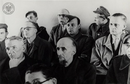 Oskarżeni w procesie pokazowym przywódcy PPS-WRN wśród strażników – zdjęcie z albumu. Widoczni na zdjęciu, od lewej: w pierwszym rzędzie – Józef Dzięgielewski (podpierający twarz dłonią) i Tadeusz Szturm de Sztrem, w drugim rzędzie – Ludwik Cohn (w okularach) i Wiktor Krawczyk, w ostatnim rzędzie – Kazimierz Pużak. Fot. z zasobu IPN