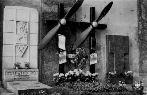 Grób Stanisława Wigury i Franciszka Żwirki na warszawskich Powązkach ze śmigłami przecinającymi ramiona krzyży. Poniżej tablice informujące o tragicznej śmierci w wypadku lotniczym 11 września 1932 roku. Z obu stron widoczne inne mogiły, w tym z lewej grobowiec z wizerunkiem Matki Bożej i wykutym poniżej napisem: „Józef Weyssenhoff / Pisarz polski / 1860-1932”. Kolekcja: Andrzej Kapłański (fot. z zasobu IPN)