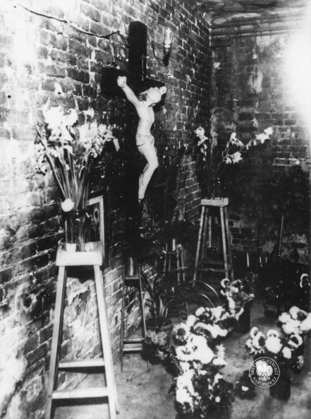 Pomieszczenie w piwnicy klasztoru ojców Jezuitów przy ulicy Rakowieckiej 61 w Warszawie, w którym 2 sierpnia 1944 r. formacja SS zamordowała (przy użyciu granatów i broni palnej) zakonników i cywilów, w tym dziesięcioletniego chłopca. Po dokonaniu zbrodni klasztor wraz z kaplicą został splądrowany. Widok pomieszczenia po usunięciu gruzów i zwęglonych zwłok, 1945 rok