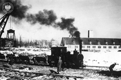 Lokomotywa wąskotorowa na tle krematorium nr II na terenie obozu KL Auschwitz-Birkenau, zima 1942-1943 r. (fot. Dietrich Kamann,  z zasobu AIPN)