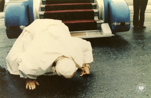 Papież Jan Paweł Drugi całuje ziemię na lotnisku Okęcie w Warszawie po wyjściu z samolotu, rozpoczynając drugą pielgrzymkę do Ojczyzny. 16 czerwca 1983 roku