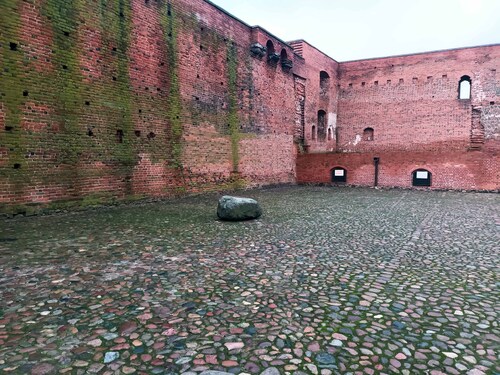Dziedziniec Zamku Książąt Mazowieckich w Ciechanowie, na którym 17 grudnia 1942 r. Niemcy dokonali egzekucji czworga żołnierzy Armii Krajowej: Bolesława Nodzykowskiego, Tadeusza Jureckiego, Zenobii Jelińskiej, Kazimiery Grzelak. W głębi kamień upamiętniający ofiary ww. egzekucji, stan obecny (fot. E. Strzeszewska, IPN)