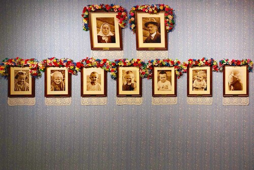 Portrety członków Rodziny Ulmów. Na górze od lewej: Wiktoria i Józef. Na dole od lewej: Stasia, Basia, Władzio, Franio, Antoś, Marysia i Wiktoria w zaawansowanej ciąży. Kompozycje kwiatowe oraz ręcznie wykonane hafty nawiązują do lokalnej tradycji. Fragment wystawy czasowej „»Błogosławieni Sprawiedliwi, albowiem…« Opowieść o Rodzinie Ulmów” przygotowanej przez Archiwum IPN we współpracy z Muzeum Polaków Ratujących Żydów podczas II wojny światowej. Markowa, 2023 r. (fot. P. Zielony)