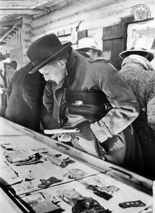 Przedstawiciel prasy zagranicznej ogląda przedmioty osobiste zamordowanych, znalezione w masowych grobach, zebrane przez Niemców na ekspozycji. W gablotach widoczne naramienniki (kapitana i podporucznika) oraz dokumenty. Katyń, 16 kwietnia – 31 maja 1943 r. Fot. z zasobu AIPN