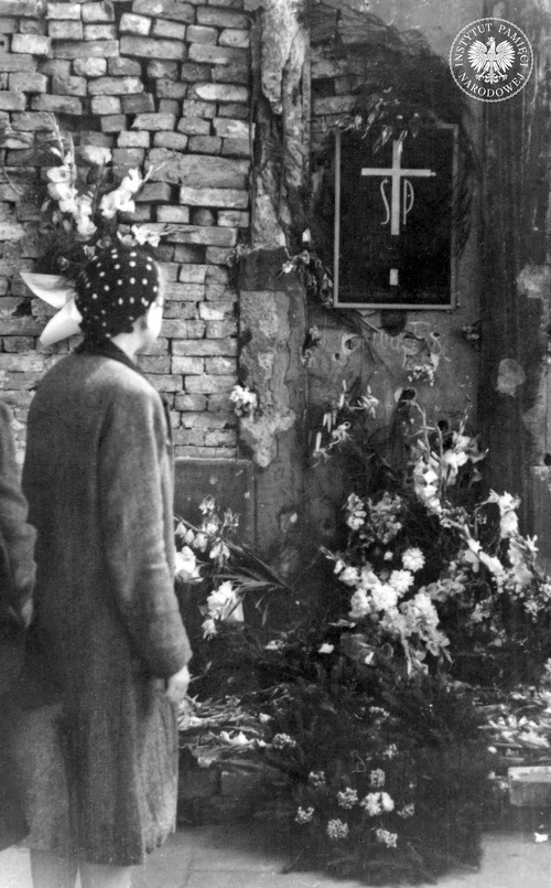 Nim wojna formalnie się zakończyła, w stolicy zaczęły powstawać tymczasowe mogiły bądź symboliczne groby. Powracający do miasta warszawiacy zaczęli spontanicznie stawiać krzyże, tablice i pamiątkowe głazy. Upamiętnienie miejsca masowej egzekucji. Zdjęcie wykonano prawdopodobnie w czerwcu 1945 r. w Alejach Ujazdowskich w Warszawie. Widoczna czarna, blaszana tablica z białym krzyżem umiejscowionym pomiędzy literami: Ś i P (fot. z zasobu IPN)