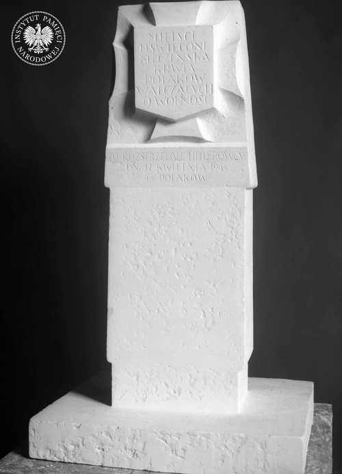 Zwycięska praca konkursowa. Model obelisku, pomnika ku czci Polaków poległych w czasie okupacji niemieckiej w formie kamiennego słupa z umieszczonym w górnej części stylizowanym równoramiennym krzyżem autorstwa artysty rzeźbiarza Karola Tchorka. Za wyborem jego pracy przemawiały: przyznanie pierwszoplanowej roli treści poprzez wyeksponowanie napisu, prostota formy ułatwiająca zachowanie powtarzalności tablic i ogólnie akceptowana symbolika (fot. z zasobu IPN)
