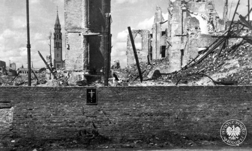 Zaraz po II wojnie światowej w Warszawie w miejscach pamięci zaczął funkcjonować wzór czarnej, blaszanej tablicy z białym krzyżem. Miejsce masowej egzekucji przy ul. Leszno, mur getta warszawskiego. Prawdopodobnie 1945 r. (fot. z zasobu IPN)