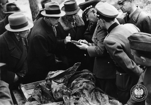 Pierwsza ekshumacja zamordowanych w Katyniu, zlecona przez Niemców. Na stole szczątki jednej z ofiar. Komisja ekshumacyjna przegląda znalezione dokumenty, które trzyma w ręku przewodniczący komisji, prof. Gerhard Buhtz (czwarty z prawej). Katyń, kwiecień 1943 r. Fot. z zasobu AIPN