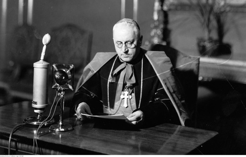 Ks. kard. prymas August Hlond przed mikrofonem w sali Pałacu Biskupiego na Ostrowiu Tumskim w trakcie nagrania przemówienia radiowego z okazji Świąt Bożego Narodzenia, 24 grudnia 1938 r. (fot. ze zbiorów NAC)