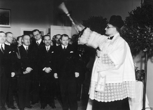 Moment poświęcenia lokalu Ośrodka Zdrowia przy ulicy Srebrnej 12 w Warszawie przez księdza Władysława Lewandowicza. Wśród zaproszonych gości widoczny m.in. prezydent Warszawy Stefan Starzyński, 9 grudnia 1938 (fot. z zasobu NAC)