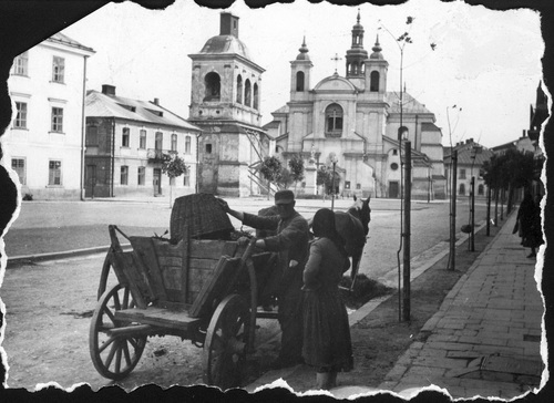 Kobieta i mężczyzna przy wozie konnym na placu przed Kolegiatą Najświętszej Maryi Panny w Stanisławowie, 1942 r. (fot. z zasobu NAC)