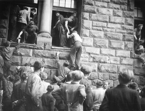 Protestujący wchodzą przez okna do Zamku Cesarskiego (wówczas siedziby Prezydium Miejskiej Rady Narodowej) przy ul. Czerwonej Armii (obecnie Święty Marcin). Poznań, 28 VI 1956 r. (fot. z zasobu IPN)