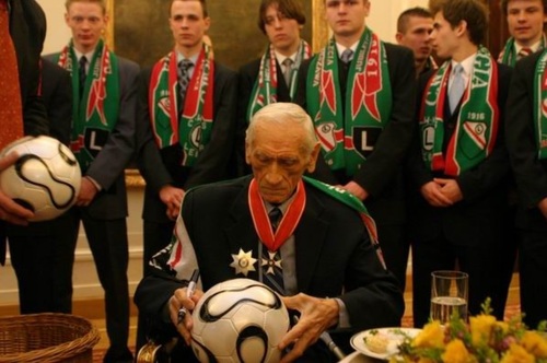 Kazimierz Górski podpisujący piłkę mistrzostw świata w Pałacu Prezydenckim tuż po odebraniu z rąk Prezydenta RP Krzyża Komandorskiego z Gwiazdą Orderu Odrodzenia Polski, 3 marca 2006 r. (fot. KPRP)