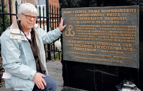 Ewa Piotrowska przy tablicy w Wołominie upamiętniającej jej babcię Zofię Brzozowską i innych nauczycieli zamordowanych przez niemieckich okupantów (fot. ze zbiorów autora)