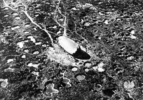 Zryte pociskami artyleryjskimi pole bitwy I wojny światowej. Artyleria powodowała nie tylko śmierć ludzi i dewastację przestrzeni, ale rujnowała też psychikę walczących. Opisano nawet nową jednostkę chorobową tzw. „szok artyleryjski” (nerwicę frontową). Wojna jednak toczy się dalej - pośród księżycowego krajobrazu widać przygotowania do podniesienia balonu obserwacyjnego (fot. z zasobu AIPN)