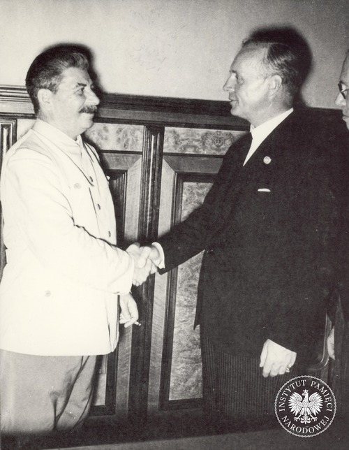 Józef Stalin (po lewej, w białym mundurze) ściska dłoń ministra spraw zagranicznych III Rzeszy Joachima von Ribbentropa (po prawej, bokiem) podczas uroczystego podpisania niemiecko-sowieckiego paktu o nieagresji (tzw. paktu Ribbentrop-Mołotow). Zdjęcie ze zbioru kopii cyfrowych fotografii dokumentujących wydarzenia II wojny światowej, pozyskanego z Narodowej Agencji Archiwów i Nagrań w College Park w stanie Maryland w USA (fot. z zasobu AIPN)