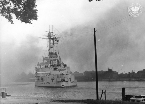 Niemiecki pancernik szkolny Schleswig-Holstein ostrzeliwuje polską placówkę (Wojskową Składnicę Tranzytową) na Westerplatte w Gdańsku, stojąc w poprzek kanału portowego. Autor: Hans Sönnke. Gdańsk, 1 września 1939 roku