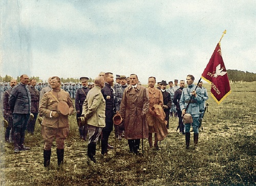 Prezes Komitetu Narodowego Polski Roman Dmowski (po środku, w płaszczu) podczas uroczystości wręczenia przez prezydenta Francji Raymonda Poincarégo sztandarów ofiarowanych przez miasta Francji tworzącej się I Dywizji polskiej, Brienne (Francja), 22 czerwca 1918 r. (ze zbiorów Biblioteki Narodowej)