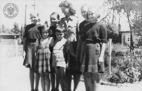 Dorrit Camil, przedstawicielka Organizacji Narodów Zjednoczonych do Spraw Pomocy i Odbudowy (UNRRA), pozuje do zdjęcia z grupą dzieci polskich repatriowanych z Niemiec, 1945-1946 (fot. z zasobu IPN)