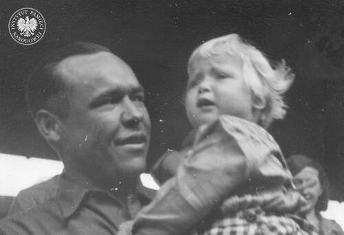 Bliżej nieznana dziewczynka – repatriantka z Niemiec – na rękach konwojenta amerykańskiego. Z tyłu po prawej stoi Dorrit Camil [?], przedstawicielka Organizacji Narodów Zjednoczonych do Spraw Pomocy i Odbudowy (UNRRA), 1945-1946 (fot. z zasobu IPN