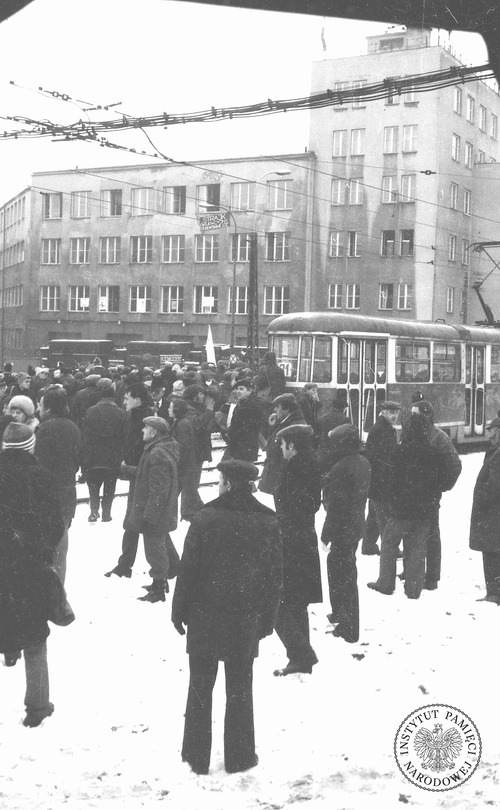 Tłum zgromadzony przed Wyższą Oficerską Szkołą Pożarniczą w dniu pacyfikacji strajku przez MO. W oknie widoczny transparent z napisem: „Strajk okupacyjny studentów WOSP”. Warszawa, 2 grudnia 1981 r. Fot. Jerzy Lech Szóstko, Edward Kucharski (fot. zasobu AIPN)