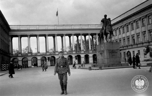 Ruch uliczny w okupowanej Warszawie przed Pałacem Saskim – na placu, który wówczas nosił imię Adolfa Hitlera. Na pierwszym planie widoczny żołnierz niemieckich wojsk lądowych (kapral), z tyłu po prawej pomnik księcia Józefa Poniatowskiego, w głębi kolumnada Pałacu Saskiego z Grobem Nieznanego Żołnierza. Warszawa, 1941 r. (fot. z zasobu IPN)