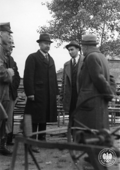 Zwiedzanie terenu byłego obozu Auschwitz-Birkenau przez delegację angielską. Zebranym o obozie opowiada sędzia Jan Sehn (drugi od prawej), 29 maja 1945 r. (fot. z zasobu AIPN)