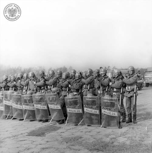 Pododdział ZOMO na ćwiczeniach na poligonie w rejonie Rzeszowa. Milicjanci w pierwszym szeregu wyposażeni w tarcze z pleksiglasu, wiosna 1982 r. (fot. z zasobu AIPN)