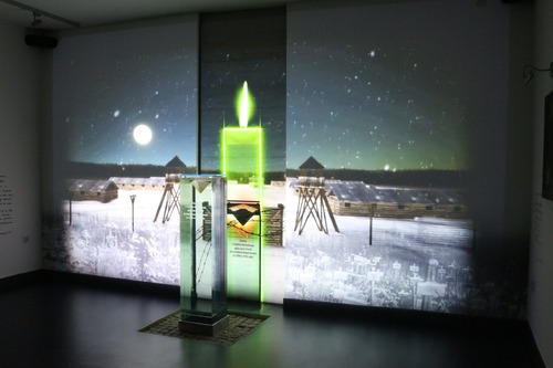 Sala zadumy – fragment ekspozycji w Centrum Dokumentacji Deportacji Górnoślązaków do ZSRR w 1945 roku (placówka ta, mieszcząca się w Radzionkowie, pełni funkcje muzealne, archiwalne, badawcze i edukacyjne). Na tle zdjęcia sowieckiego łagru znajduje się urna z podpisem: „Ziemia z Zagłębia Donieckiego, gdzie życie stracili Górnoślązacy deportowani do ZSRR w 1945 roku” (fot. Centrum Dokumentacji Deportacji Górnoślązaków do ZSRR w 1945 roku)