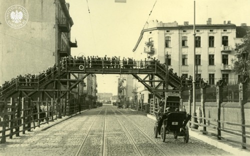 Tłum pieszych przechodzących przez drewniany most nad ul. Zgierską. Aby połączyć dwie części getta, latem 1940 r. wybudowano w tym miejscu drewnianą kładkę. Łódź, 1940 r. (fot. z zasobu AIPN)