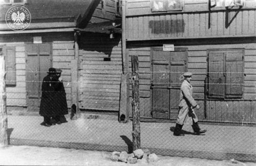 Widok na teren łódzkiego getta z ulicy po stronie tzw. aryjskiej. Na pierwszym planie ogrodzenie z siatki i drutu kolczastego. Łódź, 1940–1941 r. (fot. z zasobu AIPN)