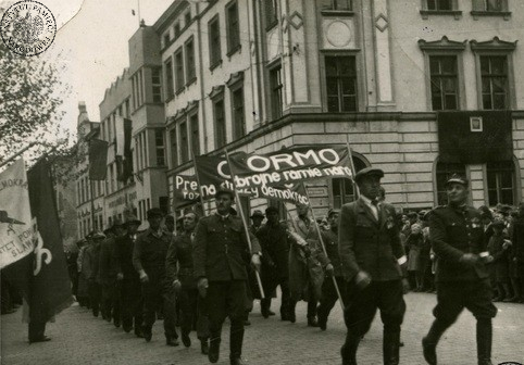 Pochód pierwszomajowy w Sławnie. Na pierwszym planie oddział Ochotniczej Rezerwy Milicji Obywatelskiej z transparentami o treści: „ORMO Zbrojne ramię narodu”, „ORMO na straży demokracji”. Brak daty rocznej wydarzenia (fot. z zasobu AIPN)