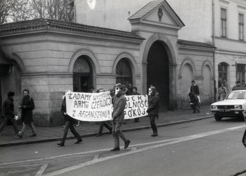 Druga akcja uliczna Ruchu WiP w Krakowie. W drodze ul. Sienną pod Konsulat Generalny ZSRS. Na czele pochodu B. Sienkiewicz z ulotkami w ręce i M. Kurzyniec w czarnym płaszczu oraz  pozostali Członkowie Ruchu WiP w maskach gazowych, grudzień 1987. Fot. z Archiwum Radosława Hugeta