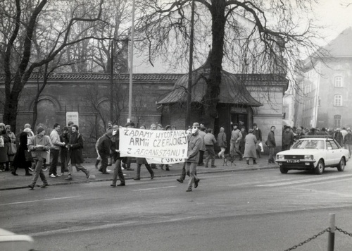 Druga akcja uliczna Ruchu WiP w Krakowie. W drodze ul. Sienną pod Konsulat generalny ZSRS. Na czele pochodu B. Sienkiewicz z ulotkami w ręce i M. Kurzyniec w czarnym płaszczu oraz  pozostali Członkowie Ruchu WiP w maskach gazowych, grudzień 1987. Fot. z Archiwum Radosława Hugeta