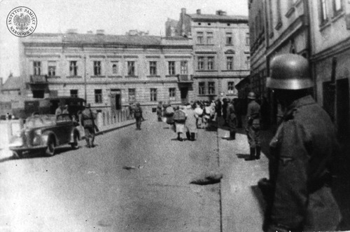 Likwidacja getta krakowskiego. Grupa Żydów (w głębi, na ulicy) zmierza prawdopodobnie w stronę obozu w Płaszowie. Na ostatnim planie i po prawej - kamienice stojące przy placu Zgody (dziś plac Bohaterów Getta). Marzec 1943 r. (fot. z zasobu AIPN)