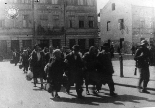 Wysiedlenie Żydów z getta krakowskiego do obozu pracy przymusowej w Płaszowie. Żydzi z walizkami, tobołkami, opuszczają w pośpiechu plac Zgody (obecnie plac Bohaterów Getta). Marzec 1943 r. (fot. z zasobu AIPN)