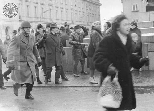 Milicjant i dwaj mężczyźni (funkcjonariusze MO lub SB w ubraniach cywilnych bądź członkowie ORMO lub tzw. aktywu robotniczego) z pałkami w dłoniach podczas rozpraszania tłumu na ulicy Nowy Świat przy pomniku Mikołaja Kopernika w Warszawie, marzec 1968 r. (fot. z zasobu IPN)