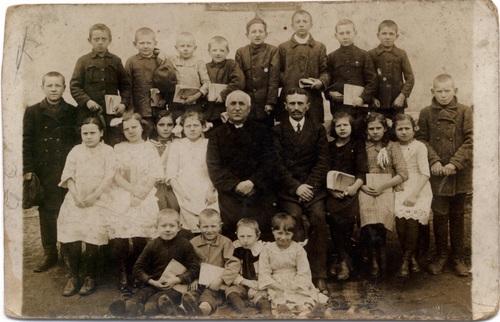 Ksiądz Jakób Rółkowski wraz z nauczycielem i dziećmi. Sztabin, dwudziestolecie międzywojenne (fot. ze zbiorów Centrum Biblioteczno–Kulturalnego w Sztabinie)