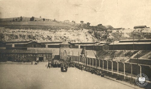 Niemiecki KL Gusen. Fragment placu apelowego obozu Gusen I z widokiem na okalające obóz druty kolczaste, znajdujące się pod wysokim napięciem, oraz granitowy, 3-metrowy mur. W głębi ściana kamieniołomu. Fotografia wykonana w 1945 r. po zajęciu i zlikwidowaniu obozu. Zdjęcie pochodzi z przekazanego do zasobu IPN archiwum Leona Królaka. Fot. z zasobu IPN