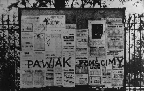 Tablica ogłoszeniowa przy ul. Brackiej w Warszawie. Na afiszach hasło: „Pawiak pomścimy”, namalowane przez harcerzy z Organizacji Małego Sabotażu „Wawer” w odpowiedzi na przeprowadzane przez Niemców masowe egzekucje, czerwiec 1943 r. (fot. z zasobu AIPN)